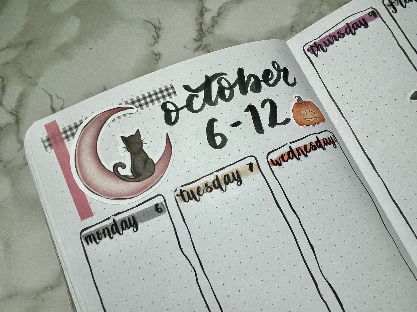 Bullet journal page with October 6-12 dates and cat sticker on a marble background
