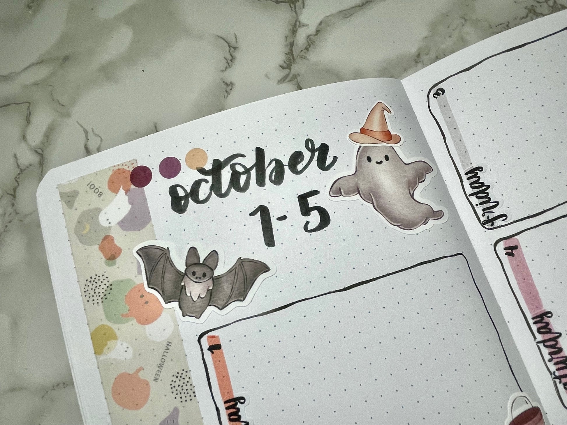 Open notebook with Halloween-themed stickers on a marble surface