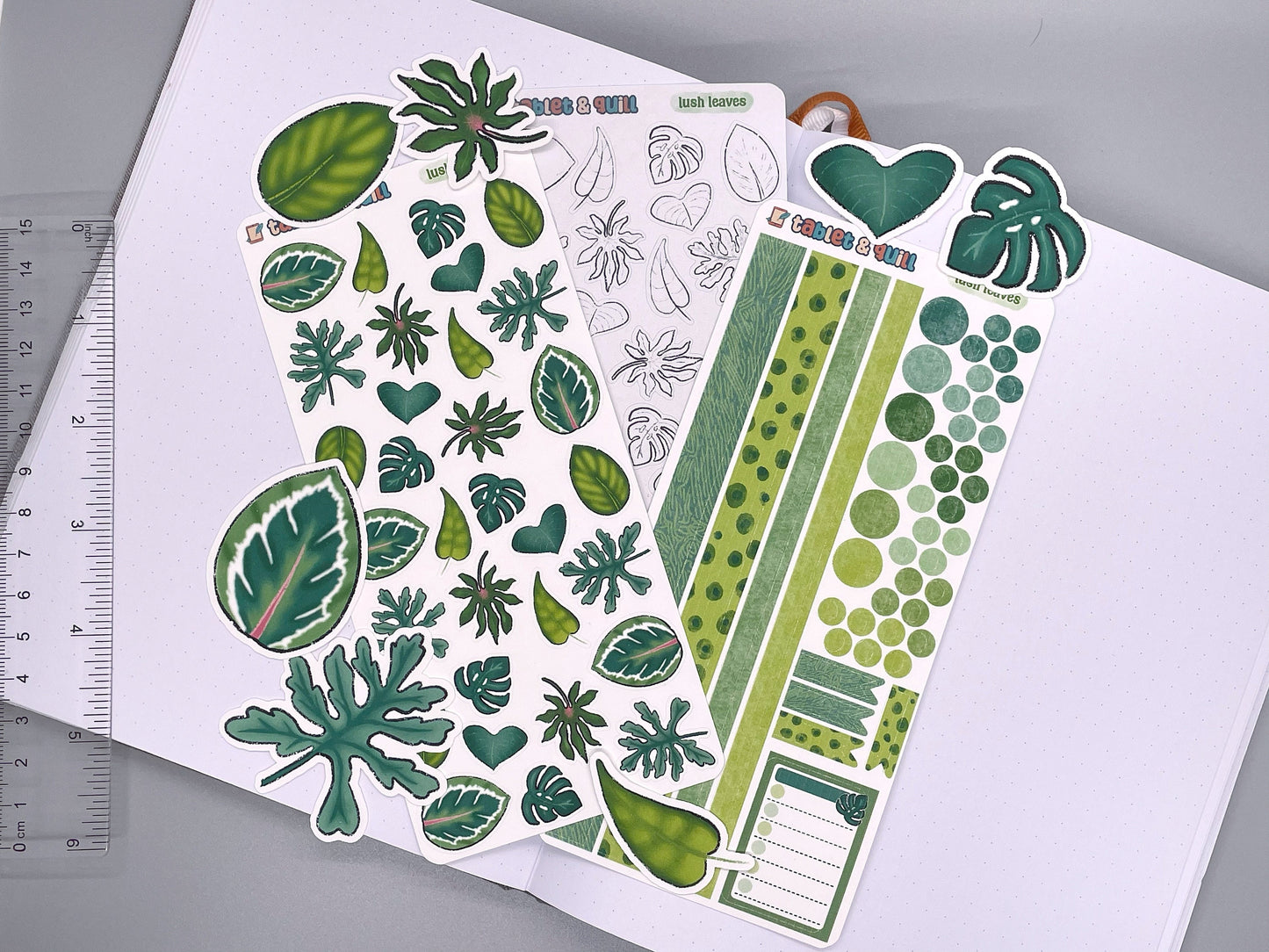 Set of leaves themed stickers for bullet journals and planners. Set includes colorable sticker sheet, decorative sticker sheet, color sticker sheet, and die cut sticker flakes. Ruler for scale on the left.