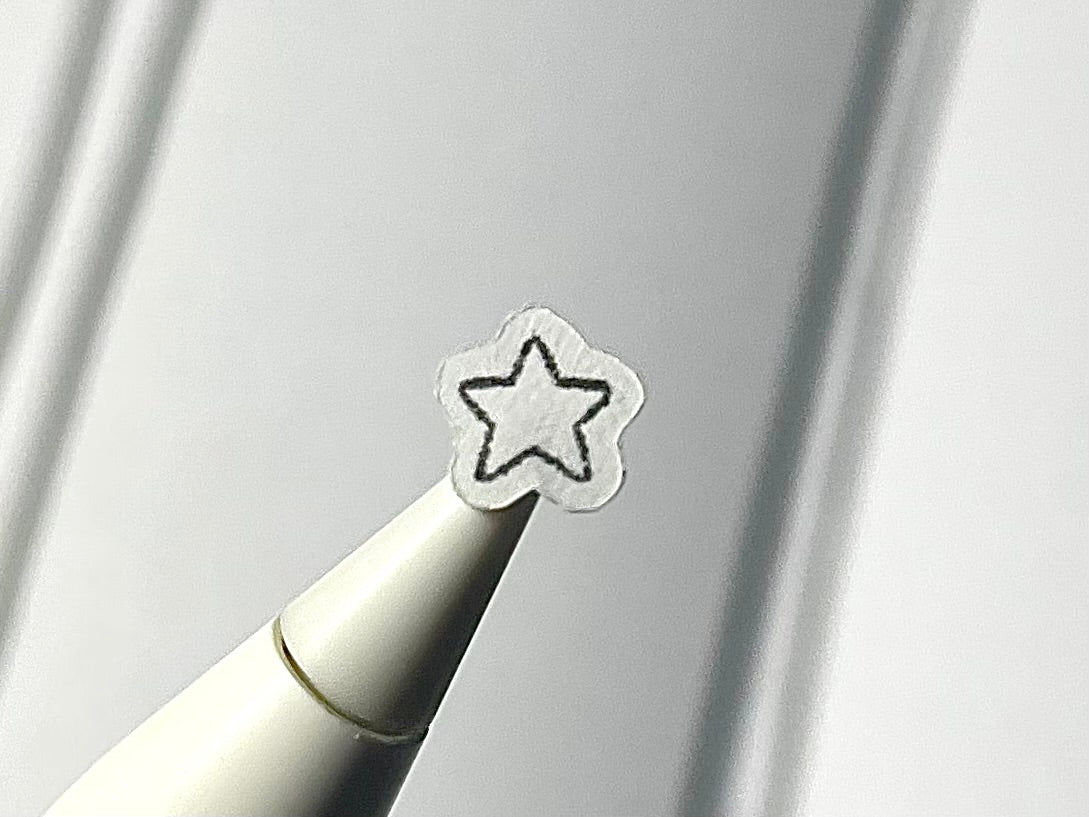 Close-up of a stylus with a star sticker on a blurry journal background.