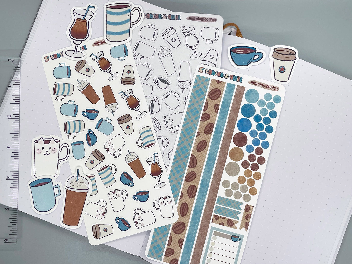 Set of coffee themed stickers for bullet journals and planners. Set includes colorable sticker sheet, decorative sticker sheet, color sticker sheet, and die cut sticker flakes. Ruler for scale on the left.