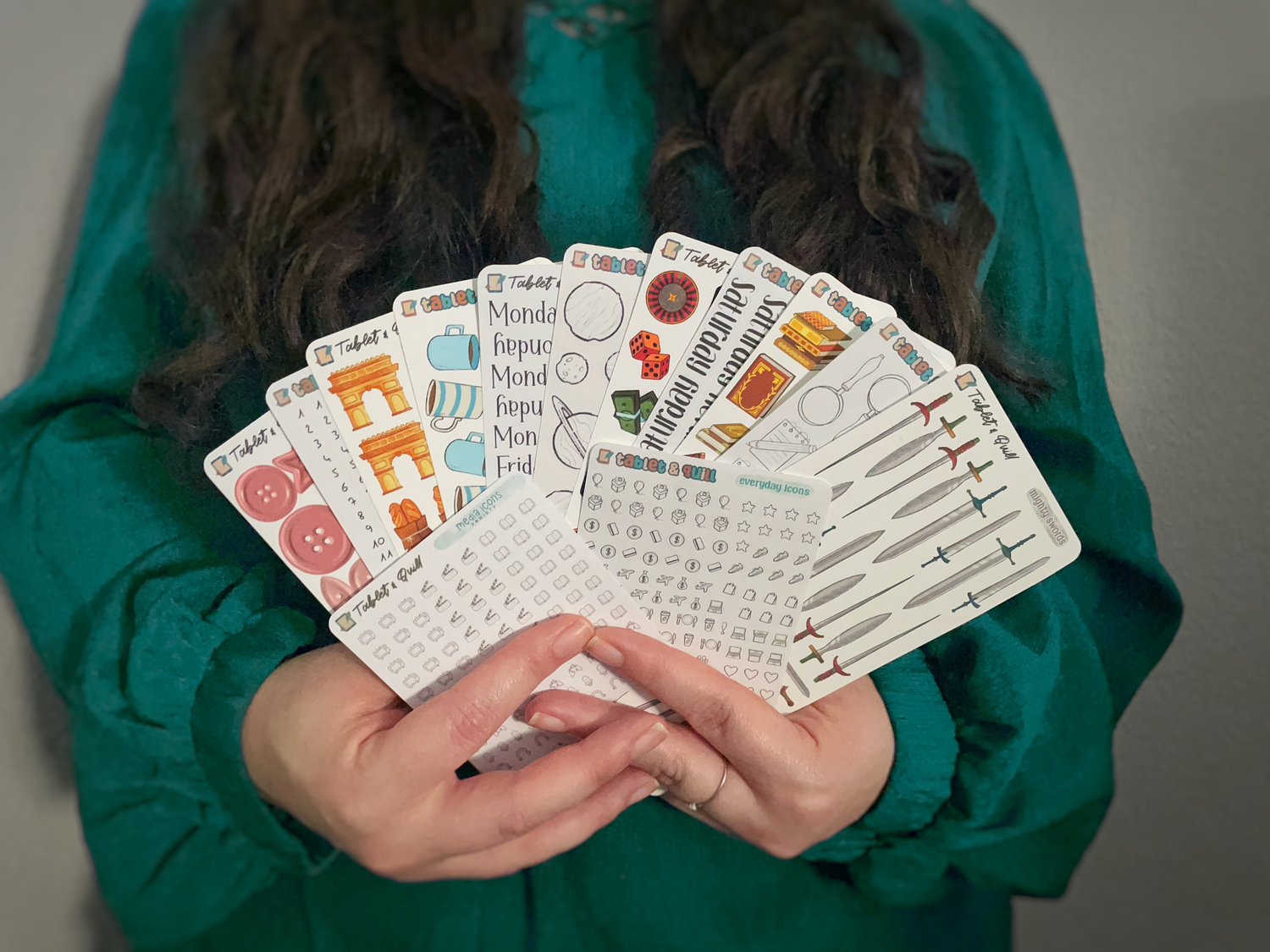 Person holding a set of planner stickers with various designs.