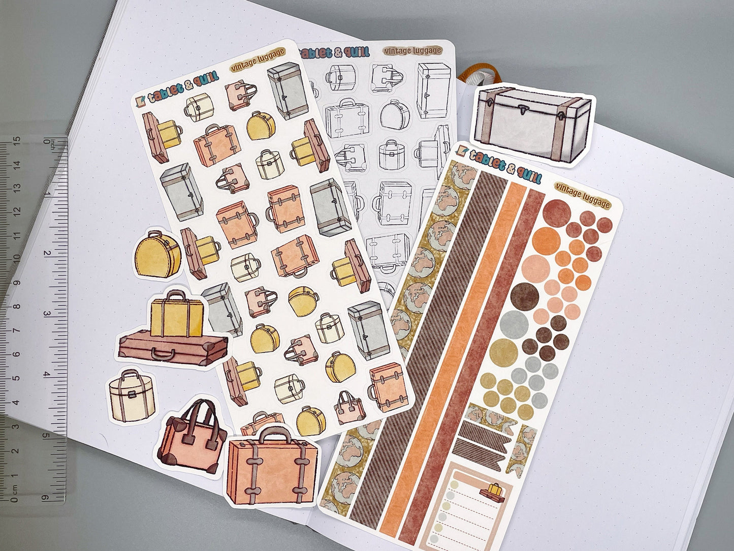 Set of vintage luggage themed stickers for bullet journals and planners. Set includes colorable sticker sheet, decorative sticker sheet, color sticker sheet, and die cut sticker flakes. Ruler for scale on the left.