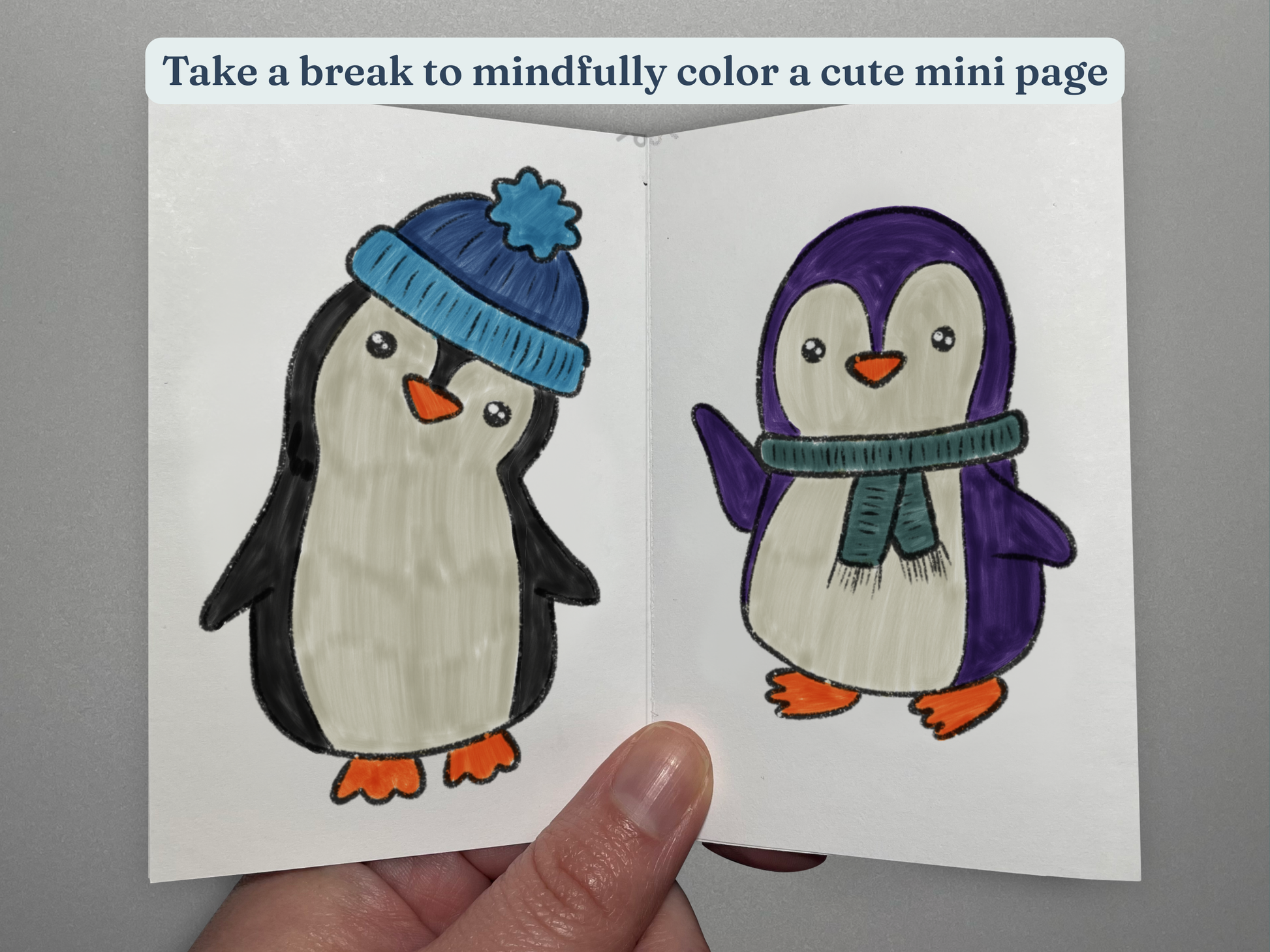 Coloring book with two penguins, one wearing a blue hat and the other a purple coat with a green scarf, held by a hand.