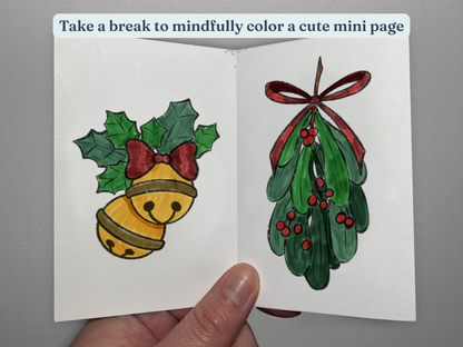 Tiny coloring book with Christmas-themed illustrations held by a hand on a gray background.