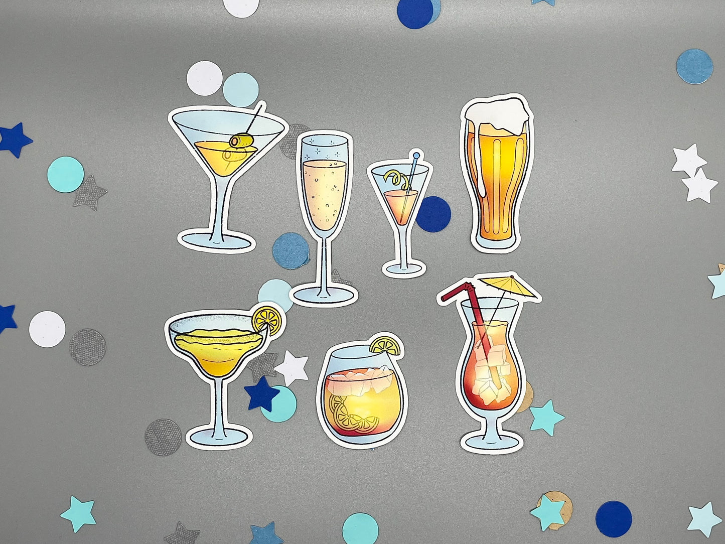 Sticker set of various cocktail glasses with drinks on a gray background with star confetti.