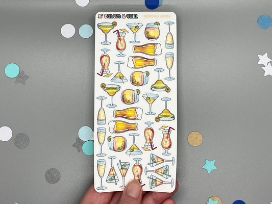 Sheet of cocktail-themed stickers held by a hand on a gray background with decorative confetti.