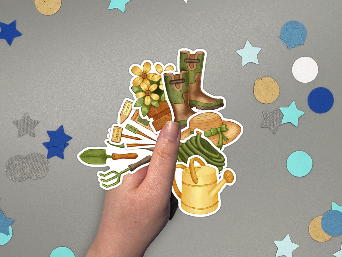 A hand holding garden themed stickers over a gray surface with confetti.