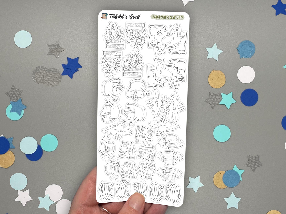 A hand holding a black and white garden themed sticker sheet over a gray surface with confetti.