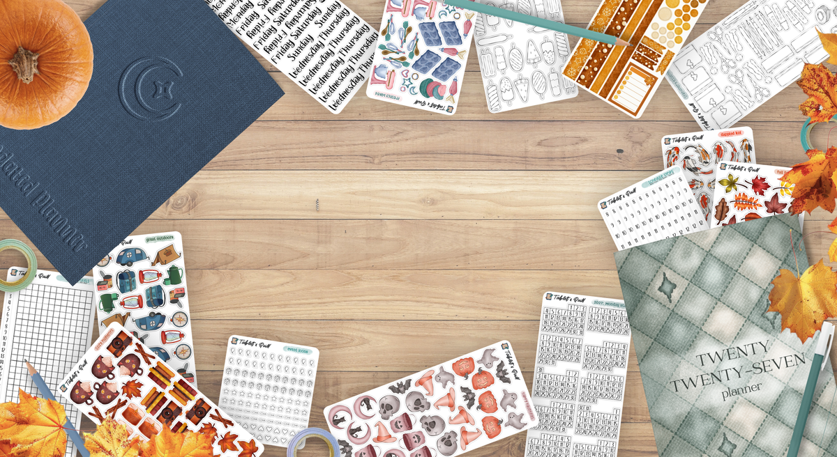 Collection of bullet journal stickers and bullet journal inspired planners on a wooden surface with stationery, autumn leaves, and a pumpkin.