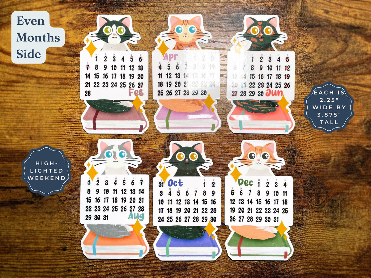 Six colorful cat-shaped monthly calendar stickers arranged on a brown wood background, with text labels including 'Even Months Side,' 'High-Lighted Weekend,' and 'Each is 2.25" wide by 3.875".