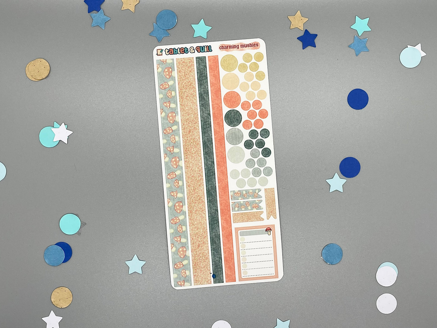 Sticker sheet with matching design as our mushroom themed stickers on a gray background with decorative stars and circles.