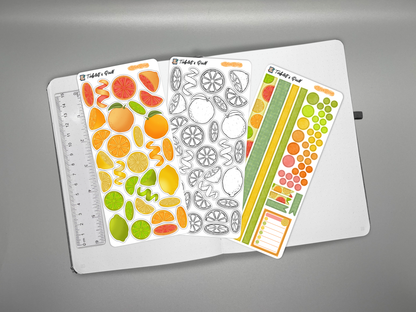 Set of colorful citrus themed bullet journal stickers on a journal with a ruler for scale over a gray background with decorative elements.