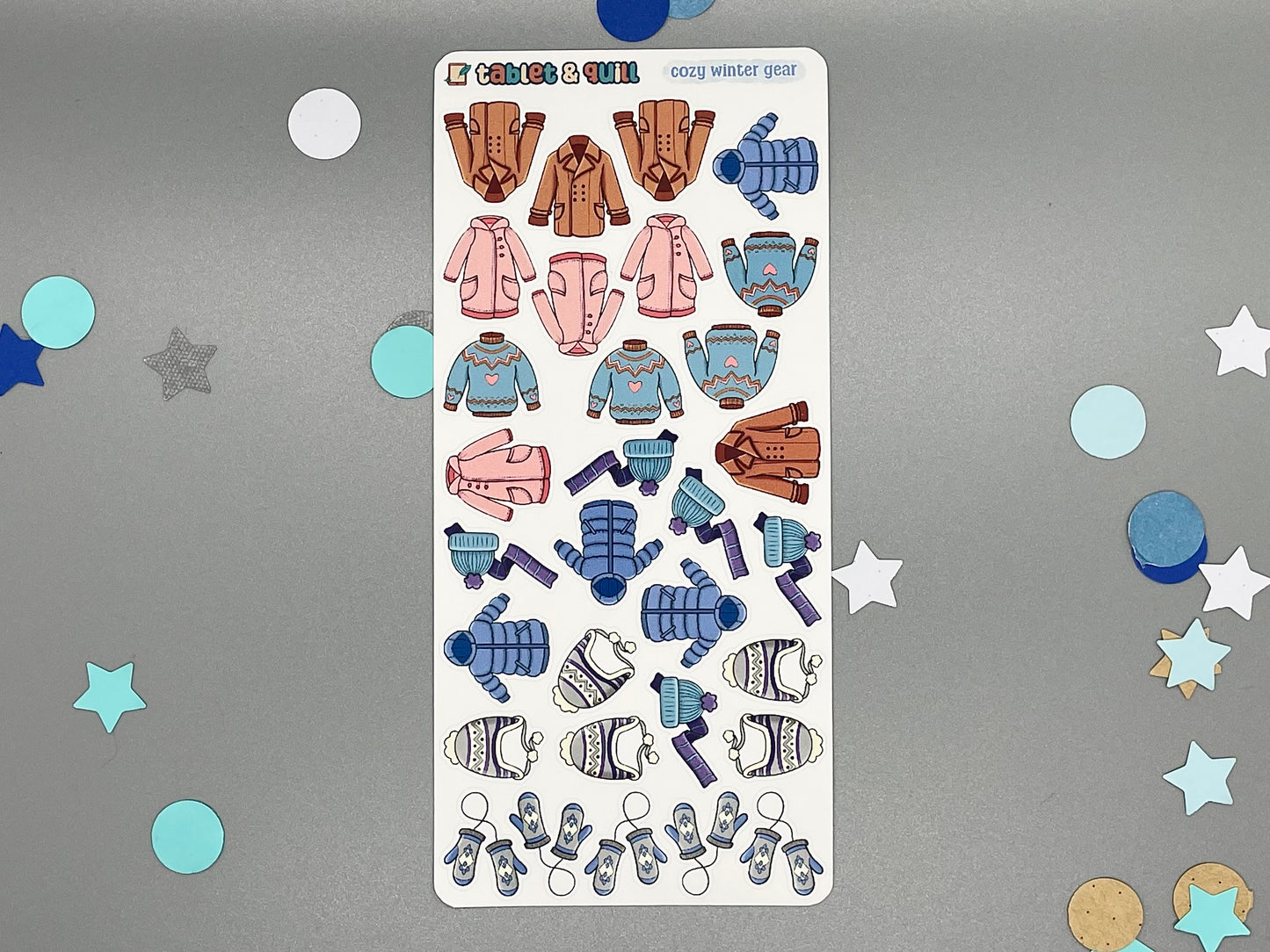 Sticker sheet of winter clothes themed stickers on a gray background with decorative stars and circles.