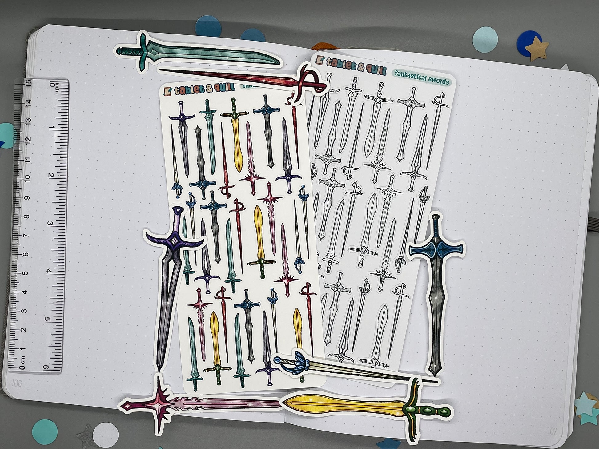 An overview image of swords themed stickers, including a color sticker sheet, a colorable sticker sheet, and die cut sticker flakes. Ruler on the left.