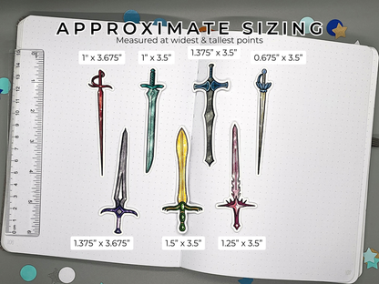 Approximate sizing of various sword stickers on a journal with a ruler for scale.