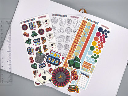 An overview image of casino themed stickers, including a color sticker sheet, a colorable sticker sheet, a decorative sticker sheet, and die cut sticker flakes. Ruler on the left. 