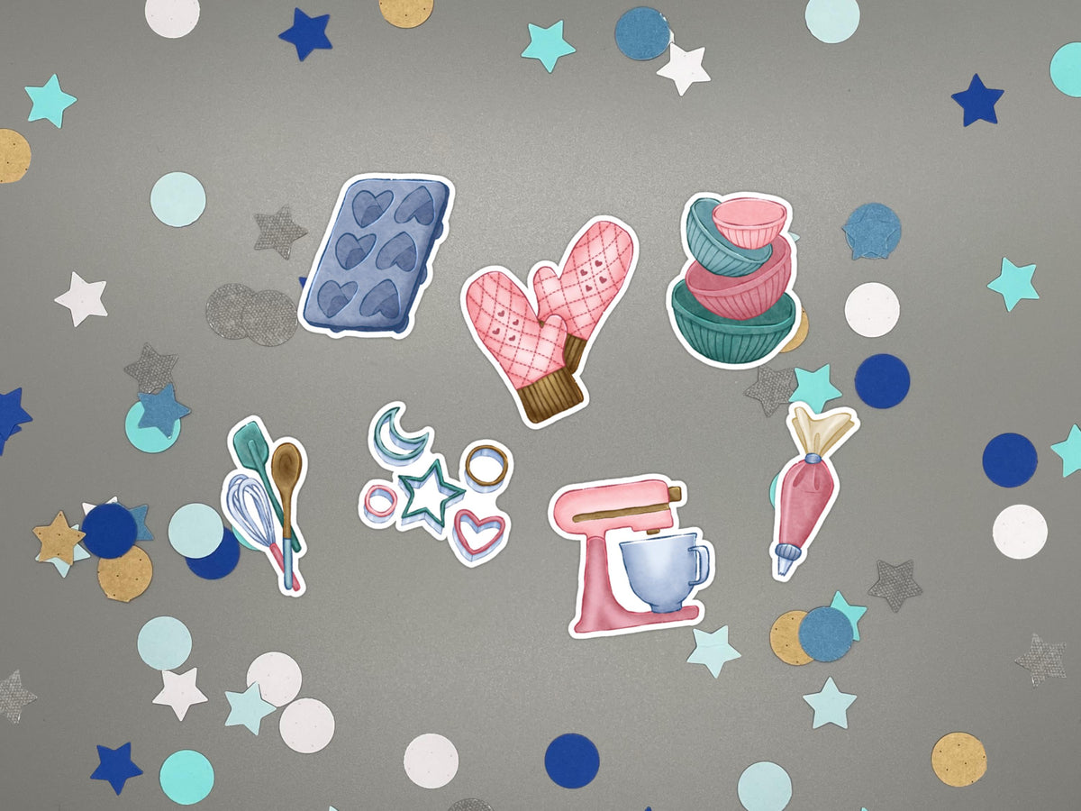 A set of baking-themed stickers on a gray background with confetti. The stickers include a blue heart cupcake mold, pink oven mitts, stacked pink and teal bowls, teal and pink spatulas, a pink stand mixer, a piping bag, and small star and heart cookie cutters.