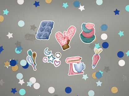 A set of baking-themed stickers on a gray background with confetti. The stickers include a blue heart cupcake mold, pink oven mitts, stacked pink and teal bowls, teal and pink spatulas, a pink stand mixer, a piping bag, and small star and heart cookie cutters.