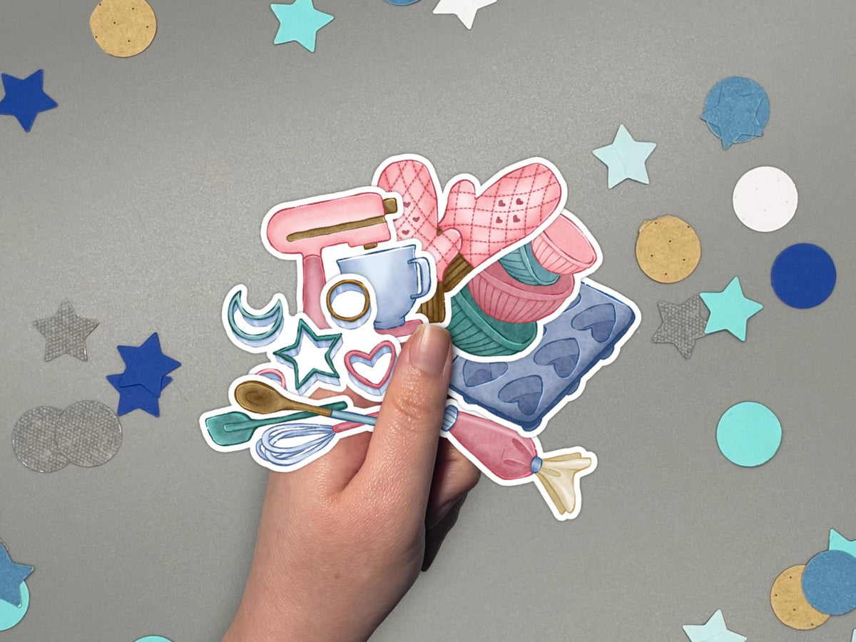 A hand holds baking themed sticker flakes over a gray surface with confetti.