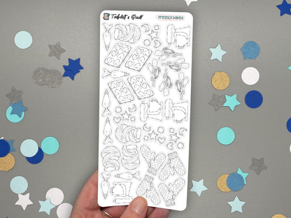 A hand holding a black and white baking themed sticker sheet over a gray surface with confetti.