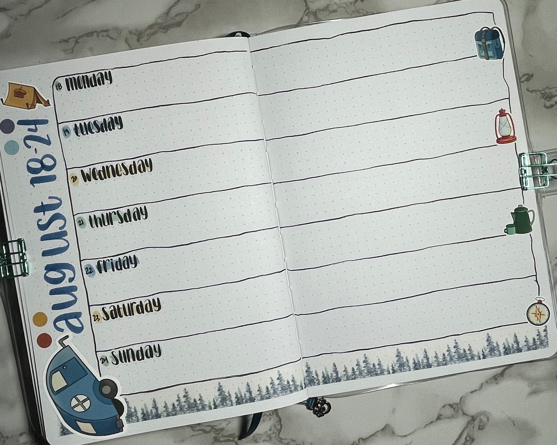 Bullet journal weekly spread decorated using camping themed stickers and hand lettered weekday stickers.