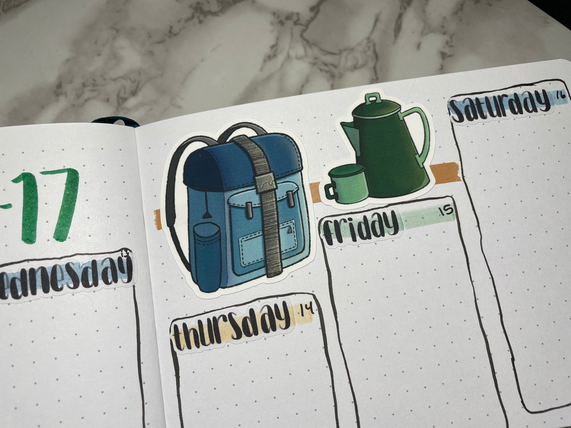 Close up of a weekly bullet journal spread decorated using camping themed stickers and hand lettered weekday stickers.