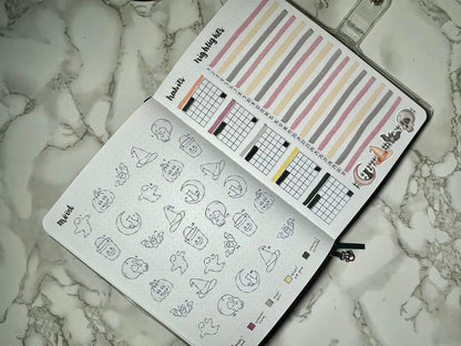Bullet journal with Halloween-themed stickers and a marble surface