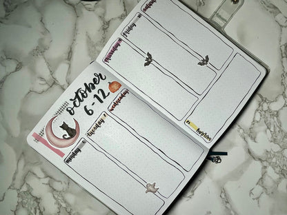 Halloween themed bullet journal weekly spread on a marble surface