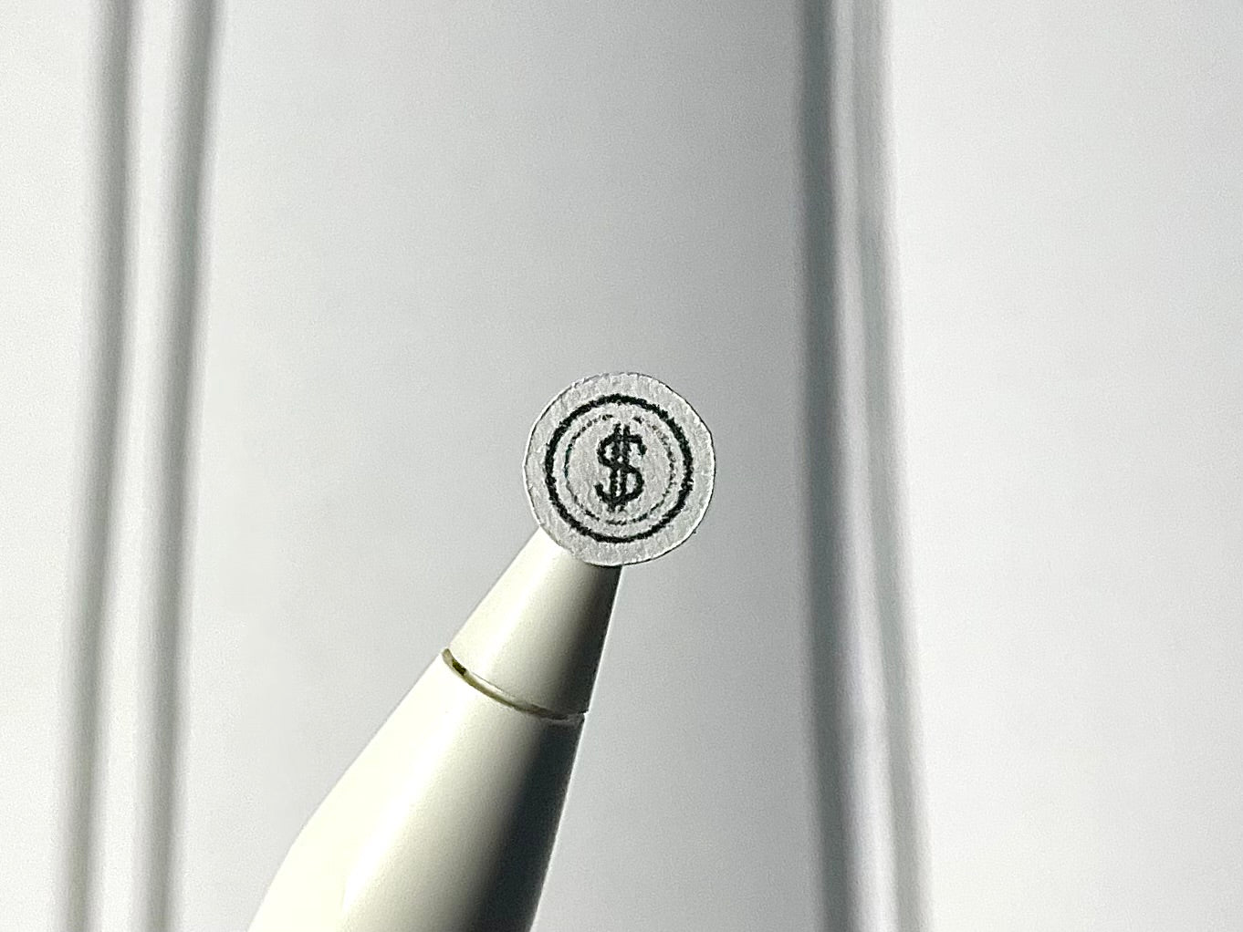 Close-up of a stylus with a coin sticker on a blurry journal background.