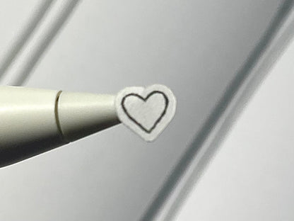Close-up of a stylus with a heart sticker on a blurry journal background.