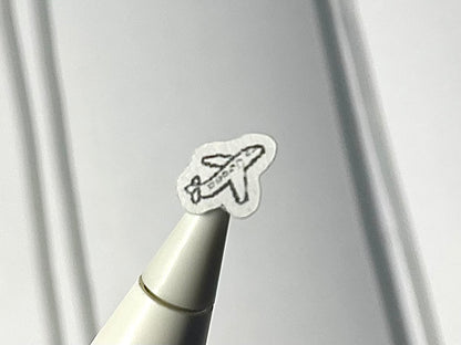 Close-up of a stylus with an airplane sticker on a blurry journal background.