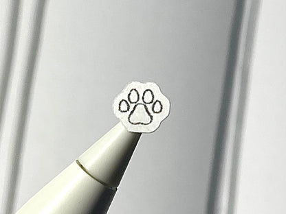 Close-up of a stylus with a paw print sticker on a blurry journal background.