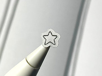 Close-up of a stylus with a star sticker on a blurry journal background.