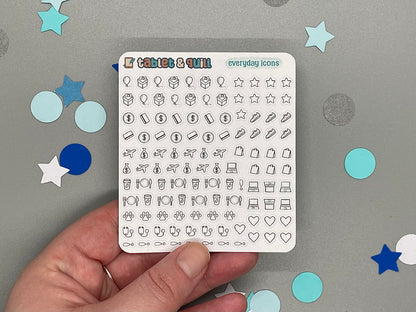 Sheet of stickers with various icons held by a hand on a gray background with decorative stars and circles.