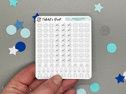 Sheet of mini planner stickers with various media icons held by a hand on a gray background with decorative stars and circles.