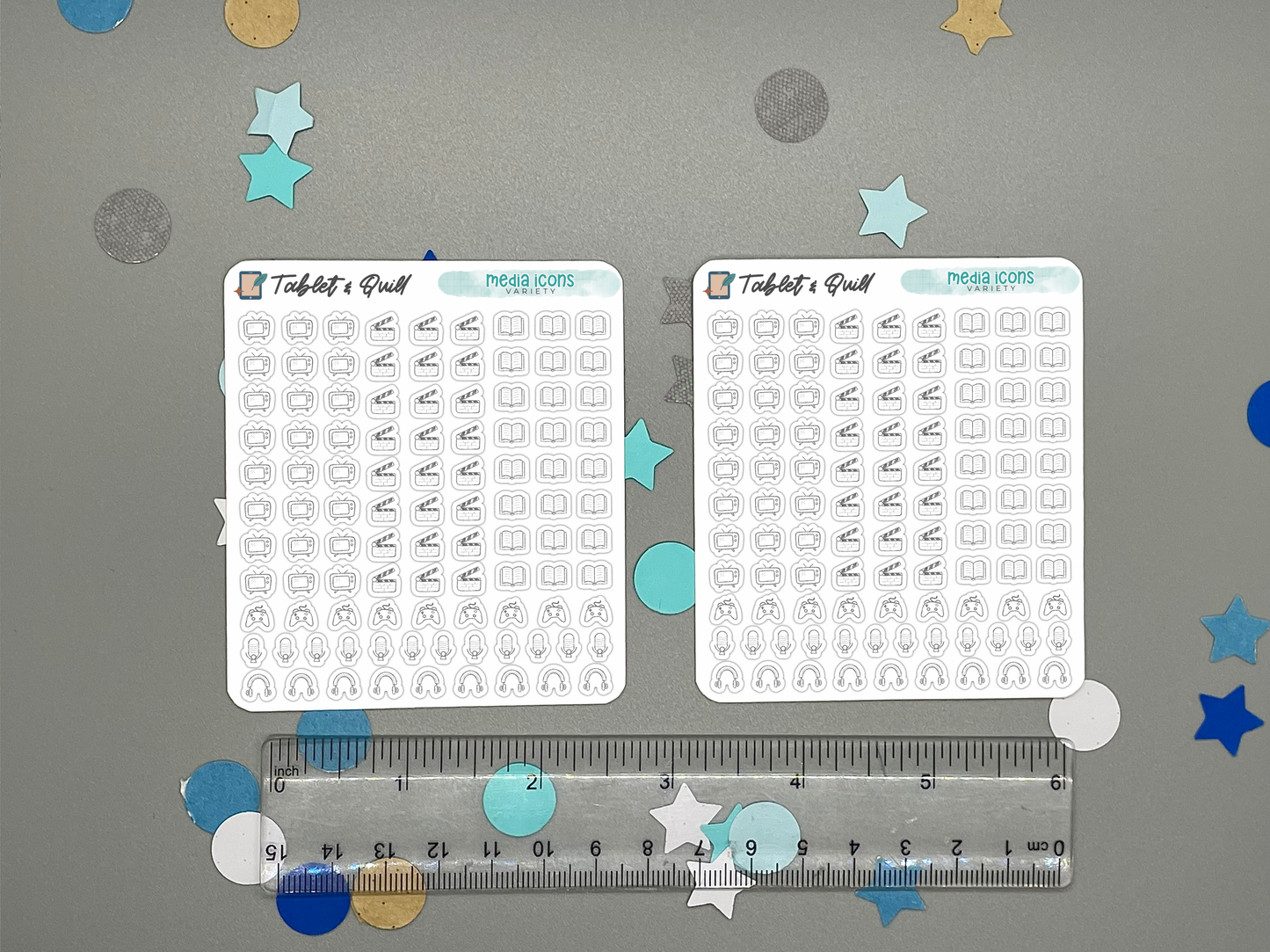 Two sheets of mini planner stickers with various media icons on a gray background with decorative stars and circles with a ruler for scale.