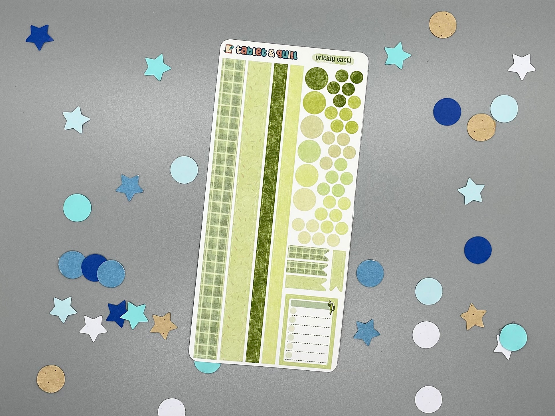 Decorative cacti themed sticker sheet with washi strips, circles, flats, and a note sticker all on a gray background with confetti.