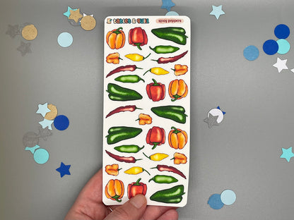 Sheet of colorful pepper stickers held by a hand with confetti stars in the background.