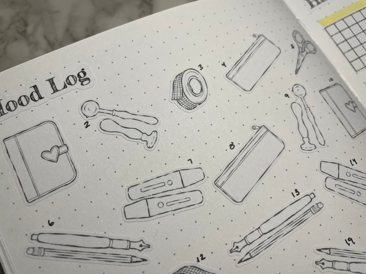 Open bullet journal monthly spread with custom header stickers and DIY color stationery themed stickers.