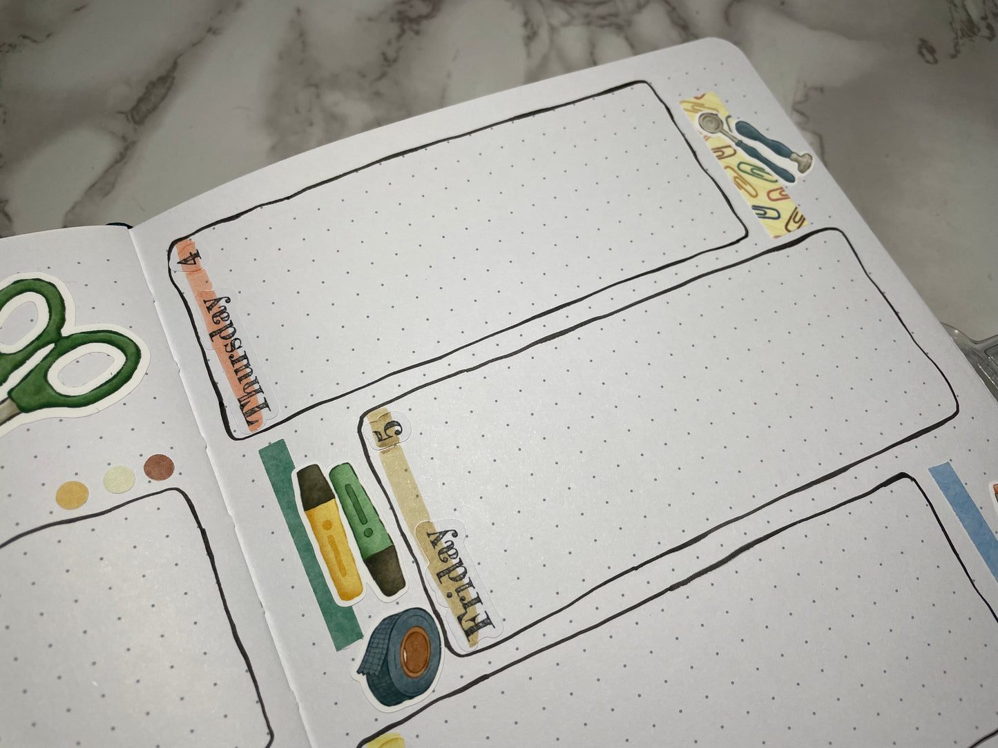 Open bullet journal weekly spread with custom header stickers and stationery themed stickers.