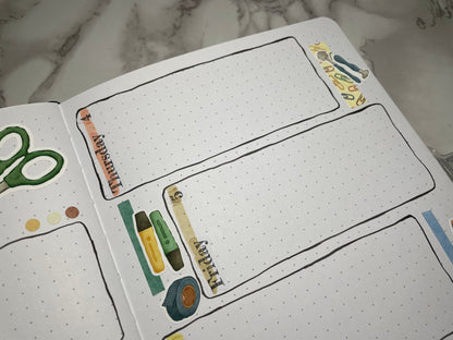 Open bullet journal weekly spread with custom header stickers and stationery themed stickers.