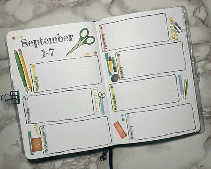 Open bullet journal weekly spread with custom header stickers and stationery themed stickers.