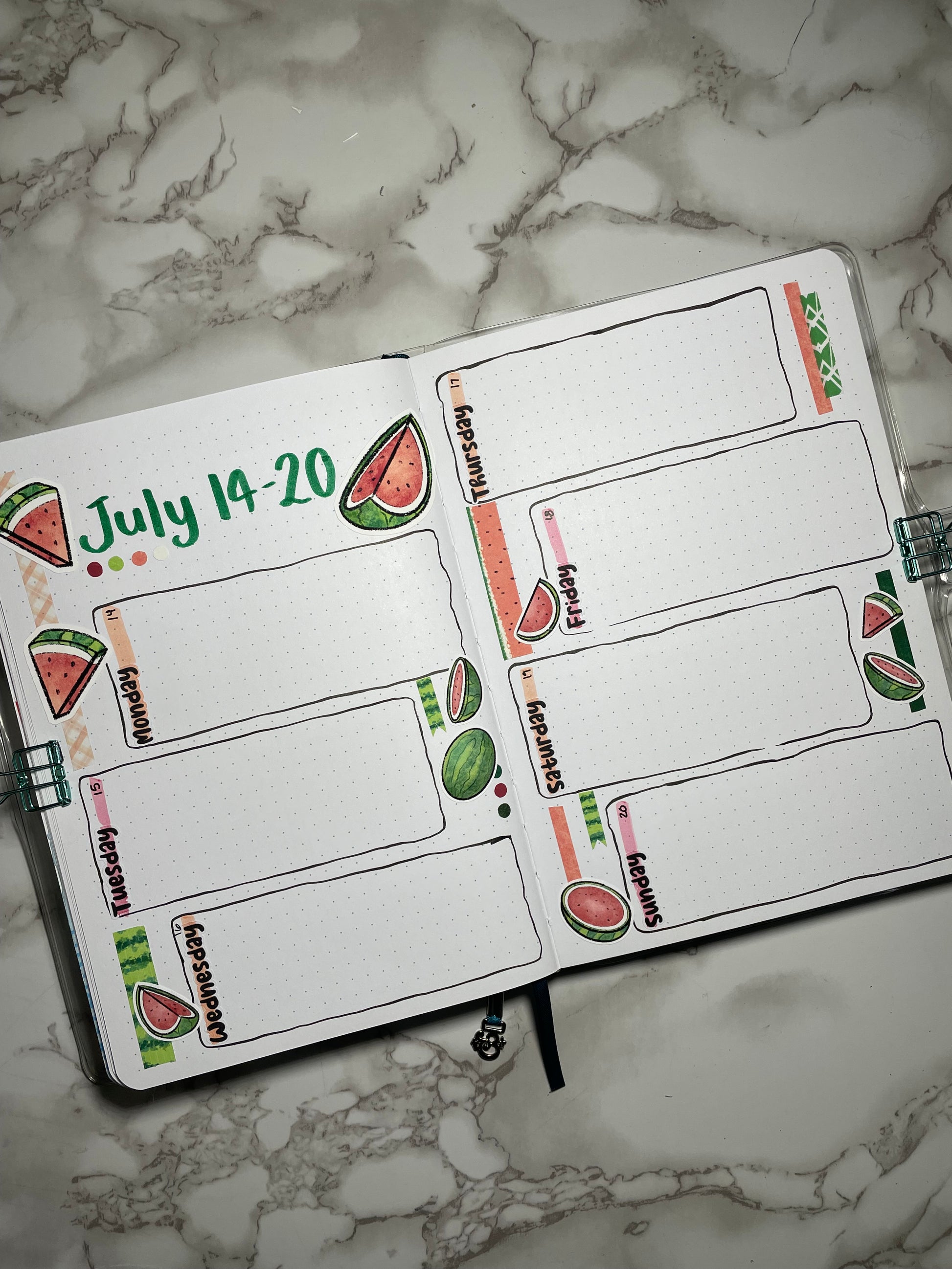Bullet journal with watermelon-themed stickers on a marble surface