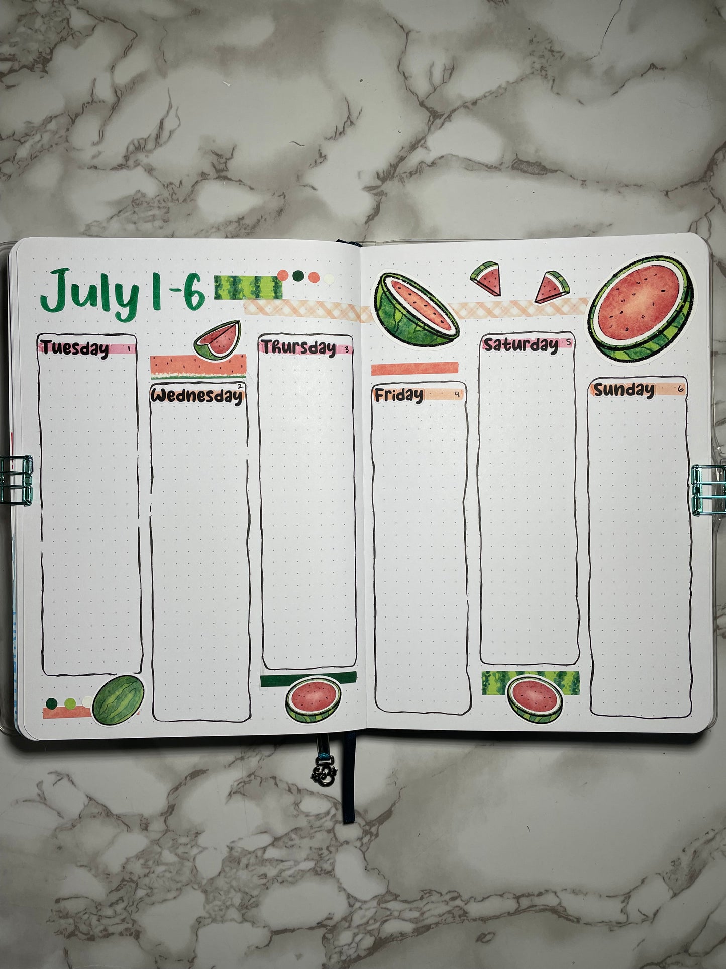 Bullet journal weekly spread with watermelon-themed design on a marble surface