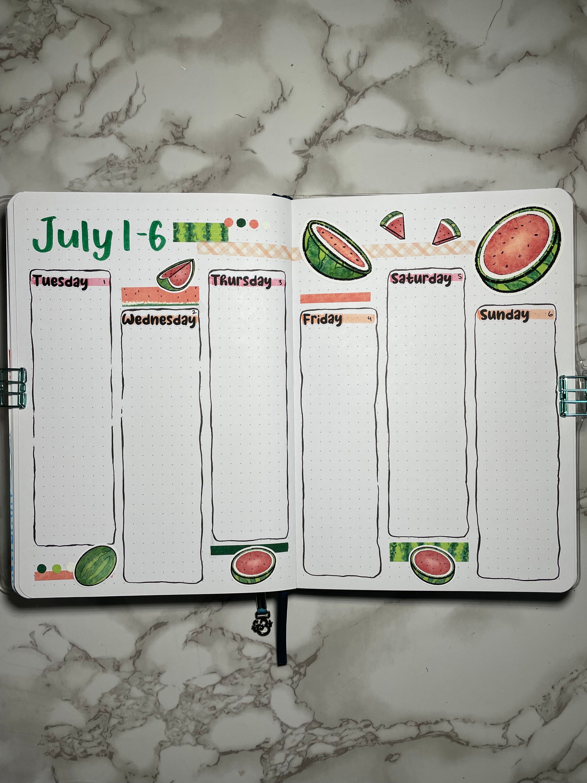 Bullet journal weekly spread with watermelon-themed design on a marble surface