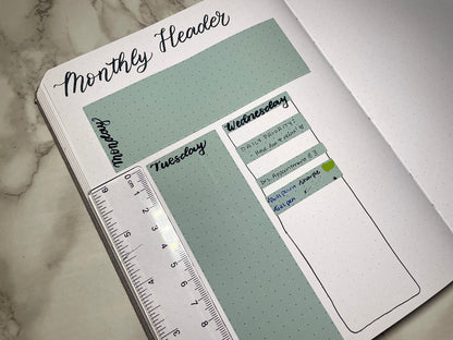 Planner stickers with days of the week labels on a marble surface